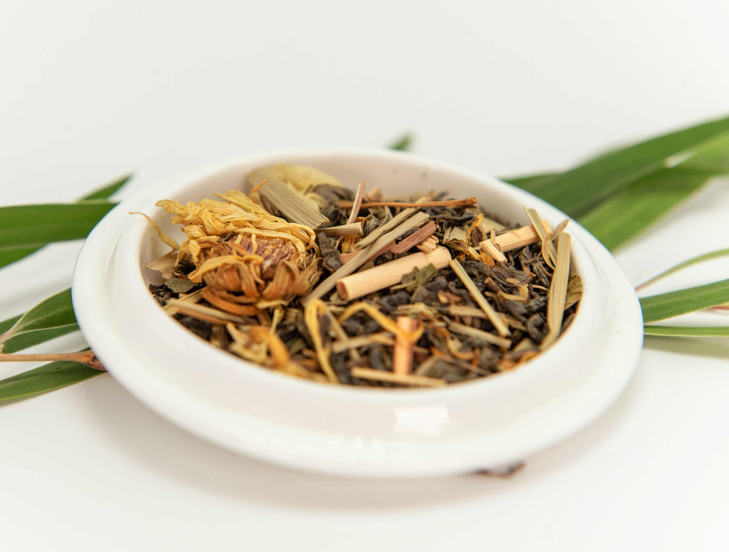 Lemon Mint Green Tea in a white dish with loose leaf blend and herbs.